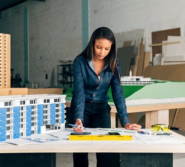 Serious-African-american-lady-with-pen-standing-near-model-of-building-on-table Lady Selling Commercial Properties